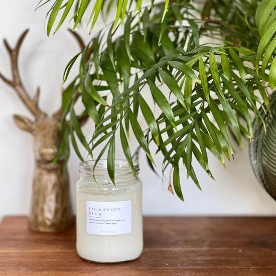 milkwick candle sitting on side table with plant and stag decor